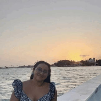 Karla Itzel Aguilar Vidal smiling and sitting in front of the sunset.